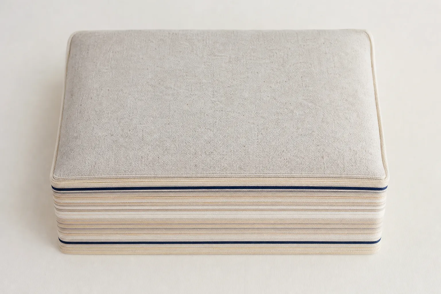 Top-down view of the STRATA pillow on a warm off-white ground, catalogue style.
